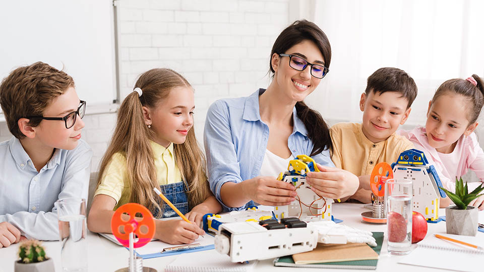 teacher and her students studying robotics